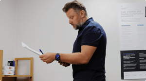Team lead reviewing papers while standing in the office, preparing to tackle licensing tasks.