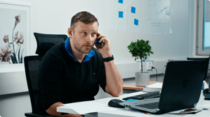 The team lead speaking on the phone looking a bit confused and annoyed.