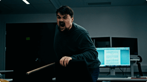 Engineer with a broom in his hand riding a office chair, ready for battle.
